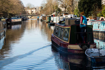 Boat, trees, birds are reflecting over Regent's Canal while people walks quietly along the river side.のeditorial素材