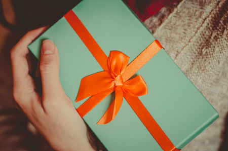 Young woman holds an elegant gift box with a bow close up toned festive backgroundの写真素材