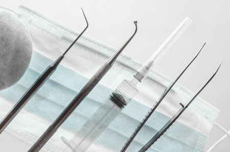 Stomatological instruments, mask and syringe on white background top view close up