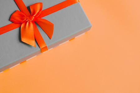 Gift with ribbon lies on light orange background top view copy space minimalistic greeting cardの写真素材