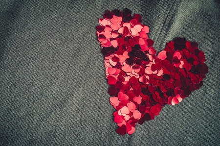 Red heart consists of small confetti on gray background. Simple romantic backdrop with copy space