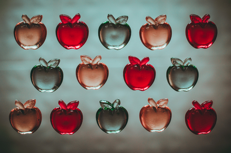 3 rows of colorful plastic transparent apples on light background top view