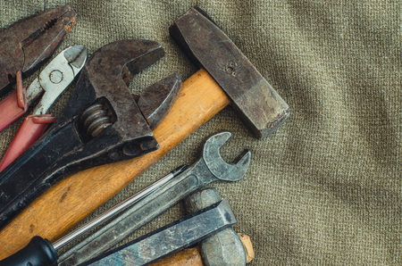 Top view different tools as hammer, screwdriver, spanner and pliers on cloth background with copy...