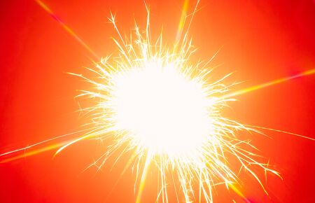 Close-up bengal light explosion with sparckles on red background. Flamy template with copy space