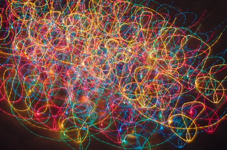 Abstract colorful background with freeze light. Christmas lights draw long curved lines on dark...