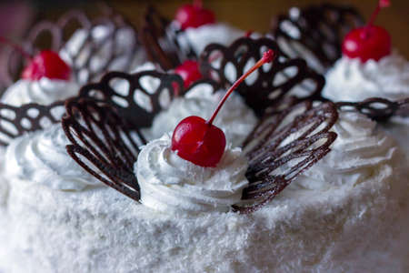 Cake with red cherry on the cream and with chocolate. Food photo.の写真素材