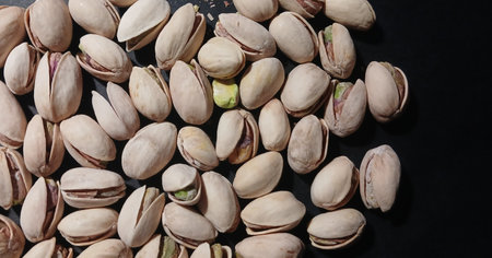 Close-up photo of pistachio nuts in shells. Natural healthy snack food with beige shells and green kernels inside. Perfect for food, nutrition, and ingredient concepts.の写真素材