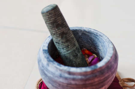 A mortar and pestle or lesung batu in Malay with crushed chilies, fried shallots and shrimp paste mixed together. Soft focus, shallow depth of field.の写真素材