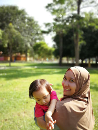 Asian muslim mother playing with daughter at park.の写真素材