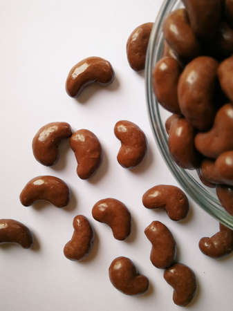 Chocolate ball candy in a bean shape is isolated over the brown background.の写真素材