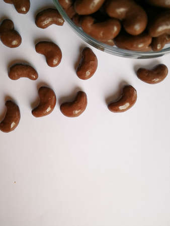 Chocolate ball candy in a bean shape is isolated over the white background.