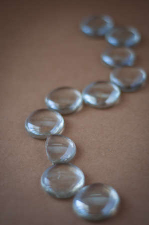 Clear marbles with light reflections on a brown background.の写真素材