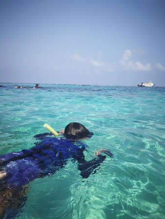 Child wearing snorkeling mask in the water.