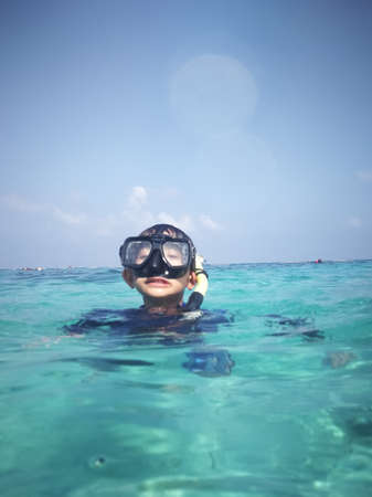 Child wearing snorkeling mask in the water.のeditorial素材
