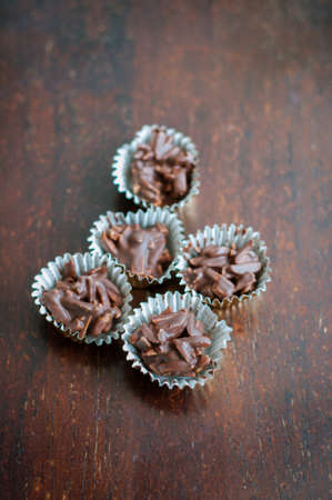 Chocolate Covered Almonds in golden paper cups on a wooden background.