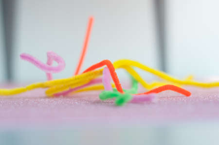 Neon colored pipe cleaners on a pink background. Messy and crumpled concept, metaphor.の写真素材