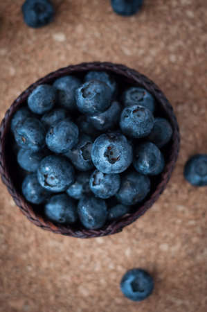 Freshly picked blueberries in woven natural screw pine leaf bowl. Juicy and fresh blueberries with on rustic table. Bilberry on wooden Background. Blueberry antioxidant. Concept for healthy eating.の写真素材