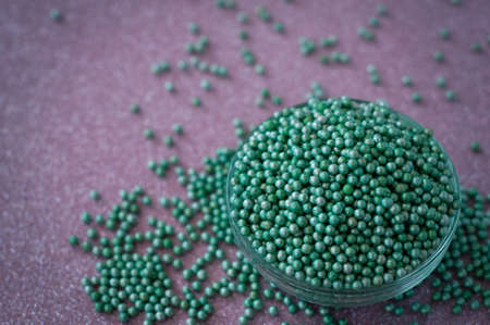 Green ball crystal sugar sprinkles dots, on glitter pink background, decoration for confectionery.  Sugar, sweetness, diabetes concept.の写真素材