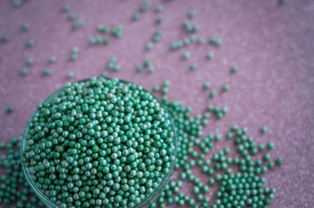 Green ball crystal sugar sprinkles dots, on glitter pink background, decoration for confectionery.  Sugar, sweetness, diabetes concept.の写真素材