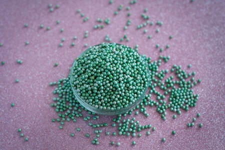 Green ball crystal sugar sprinkles dots, on glitter pink background, decoration for confectionery.  Sugar, sweetness, diabetes concept.の写真素材
