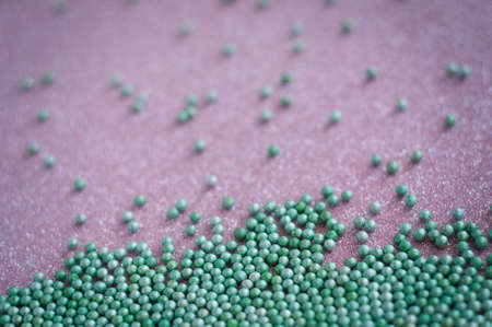 Green ball crystal sugar sprinkles dots, on glitter pink background, decoration for confectionery.  Sugar, sweetness, diabetes concept.の写真素材