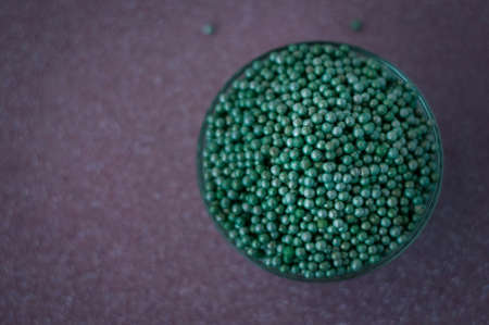 Green ball crystal sugar sprinkles dots, on glitter pink background, decoration for confectionery. ...