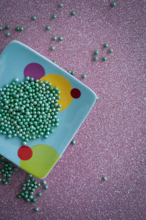 Green ball crystal sugar sprinkles dots, on glitter pink background, decoration for confectionery.  Sugar, sweetness, diabetes concept.の写真素材