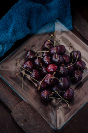 Fresh cherry on clear plate on wooden background. fresh ripe cherries. sweet cherries.の写真素材