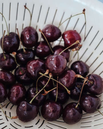 Fresh cherry on white basket. fresh ripe cherry being washed before eaten.