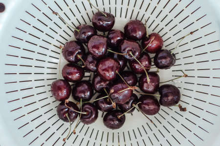 Fresh cherry on white basket. fresh ripe cherry being washed before eaten.