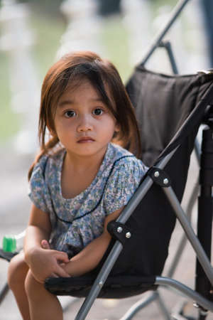 Toddler with puzzled face sitting in the stroller.の写真素材