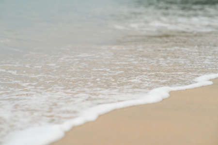 Soft waves with foam of ocean on the sandy beach background