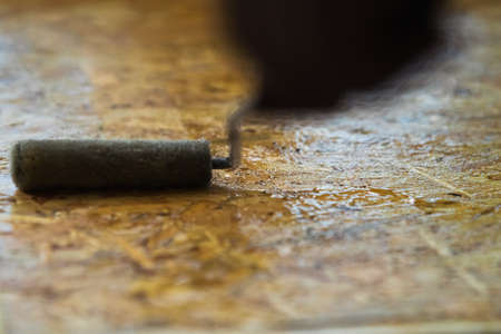 Roller paint brush lacquered osb wooden board. DIY, carpenting and construction concept.