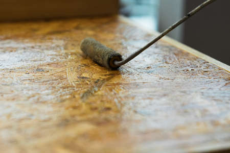 Roller paint brush lacquered osb wooden board. DIY, carpenting and construction concept.