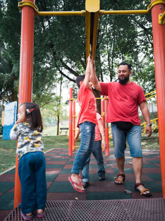 Asian family playing in the monkey bar playground in the morning.の写真素材