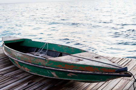 Old wooden boat sitting on the pier overlooking the beautiful Semporna turquoise sea.の写真素材