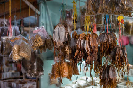 Dried fish tied into several bundles for sale, hanging from above, in a local fish market in Semporna, Sabah.の写真素材