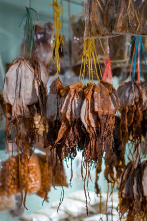 Dried fish tied into several bundles for sale, hanging from above, in a local fish market in Semporna, Sabah.の写真素材