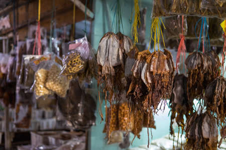 Dried fish tied into several bundles for sale, hanging from above, in a local fish market in Semporna, Sabah.の写真素材