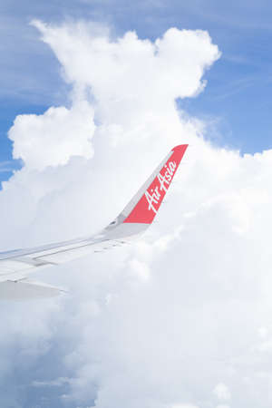 Tawau, Malaysia - Nov 24, 2019: Air Asia aircraft wing flying over clouds on a sunny day.のeditorial素材