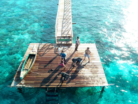 Top down aerial view over the end of wooden Jetty with unidentified kids on it.の写真素材