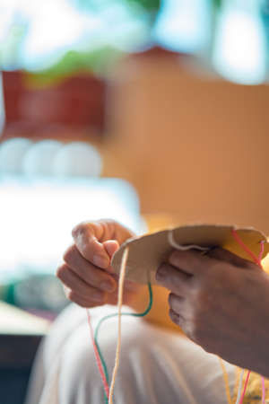 Making a braided friendship bracelet using a cardboard and yarn.の写真素材