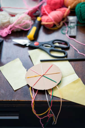 Making a braided friendship bracelet using a cardboard and yarn.の写真素材