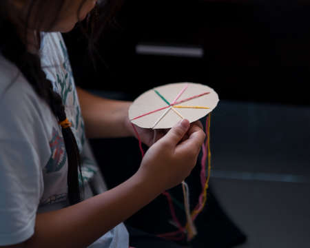 Making a braided friendship bracelet using a cardboard and yarn.