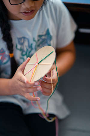 Making a braided friendship bracelet using a cardboard and yarn.の写真素材