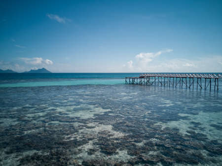 Blue shallow sea with coral reef and fluffy clouds on the horizonの写真素材