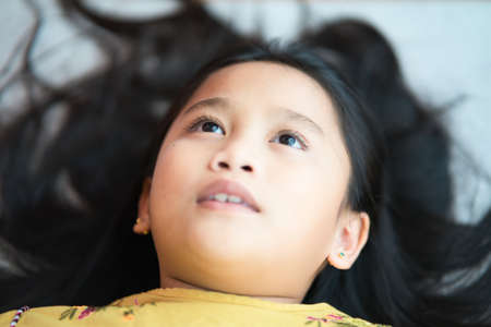 moody kid, serious kid, optimistic girl, positive girl; portrait of happy, positive, asian girl; female child kid model studio isolatedの写真素材