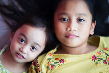 Portrait of asian siblings sisters looking with cute face looking at the camera.の写真素材