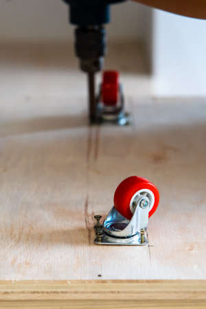 Fixing castor wheel to the wooden plywood, furniture making.の写真素材
