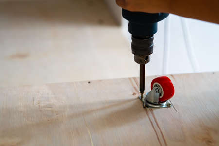 Fixing castor wheel to the wooden plywood, furniture making.の写真素材
